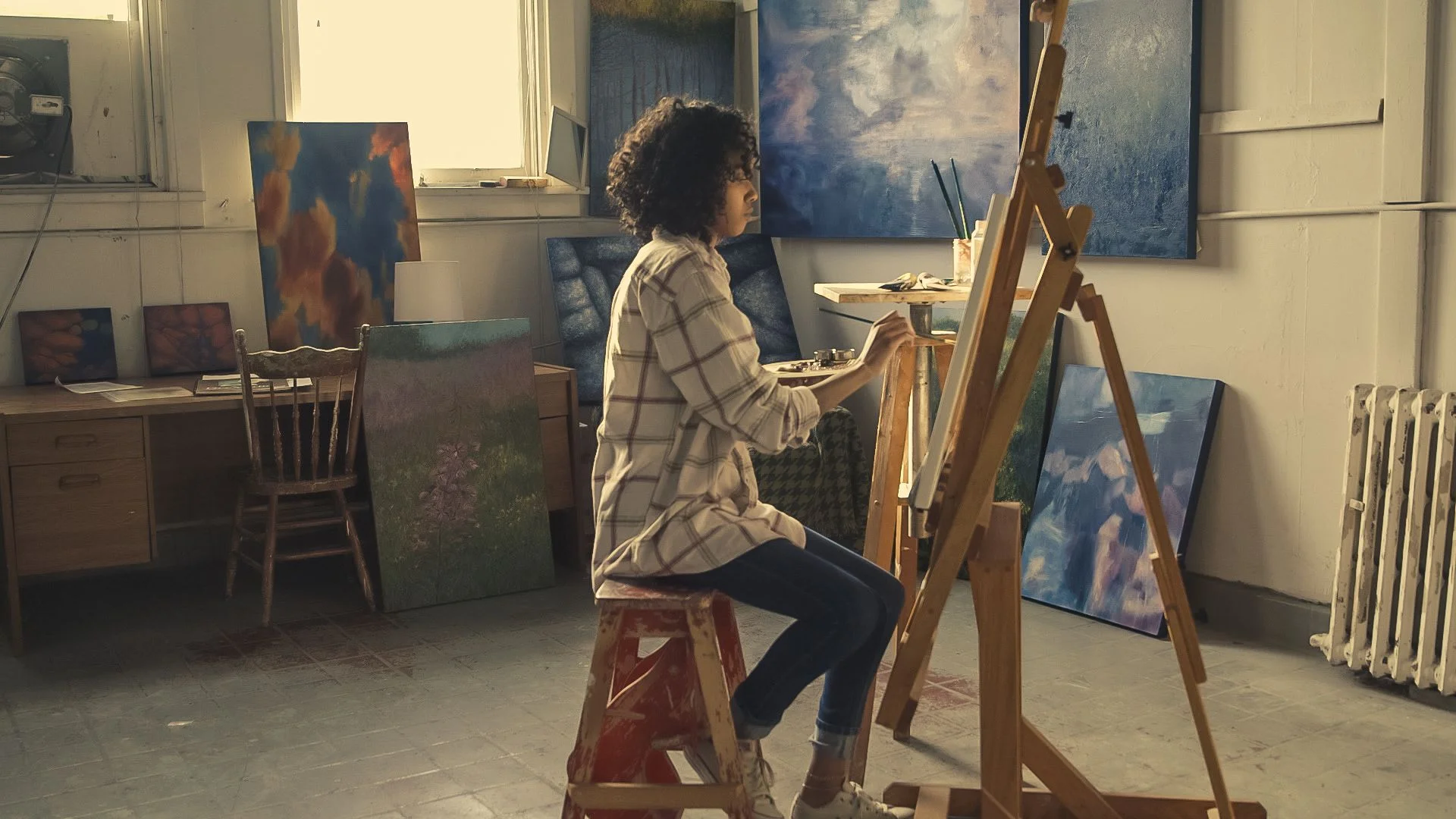 Artist working at an easel in a bright studio space