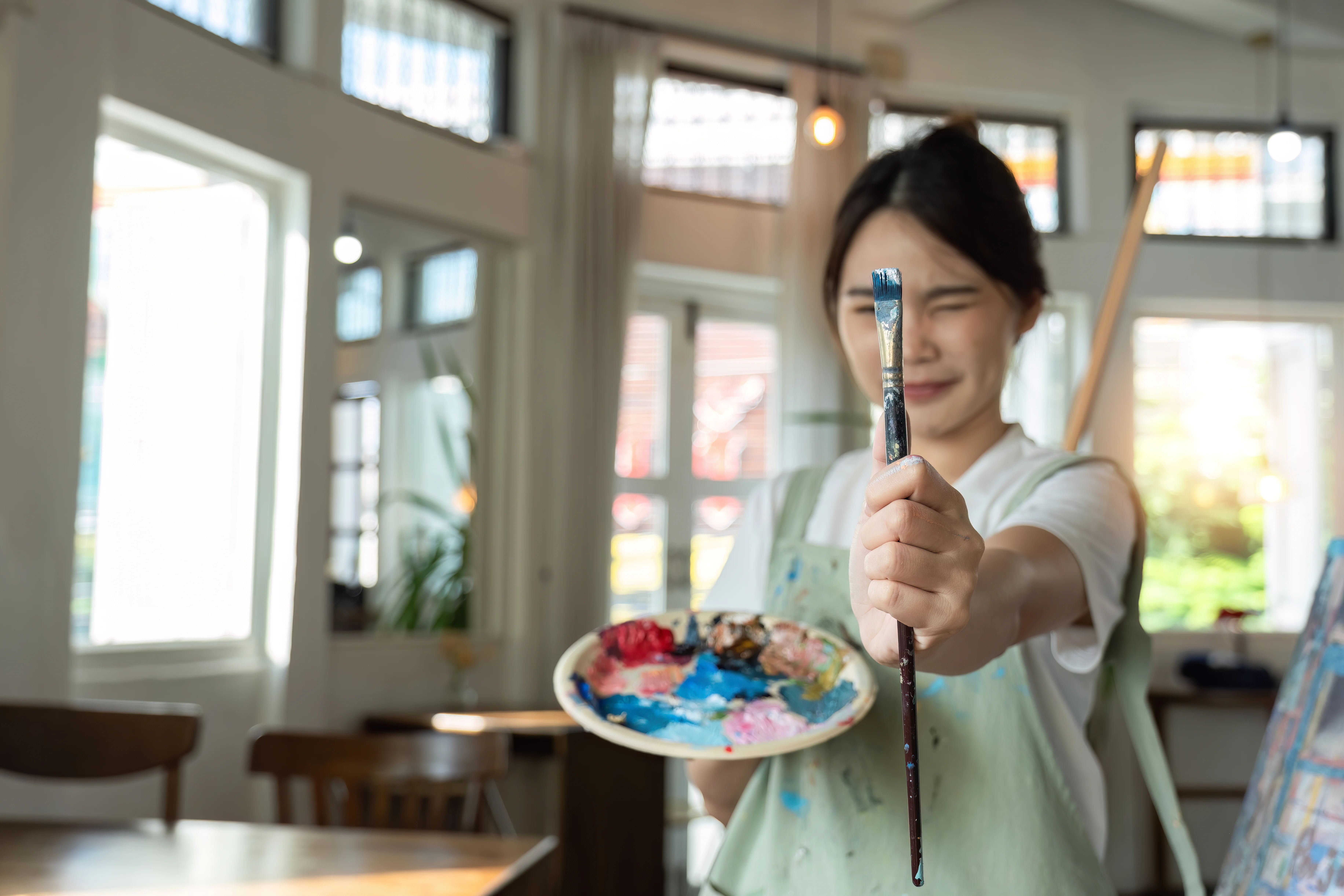 Happy young woman holding a paintbrush and sight measuring